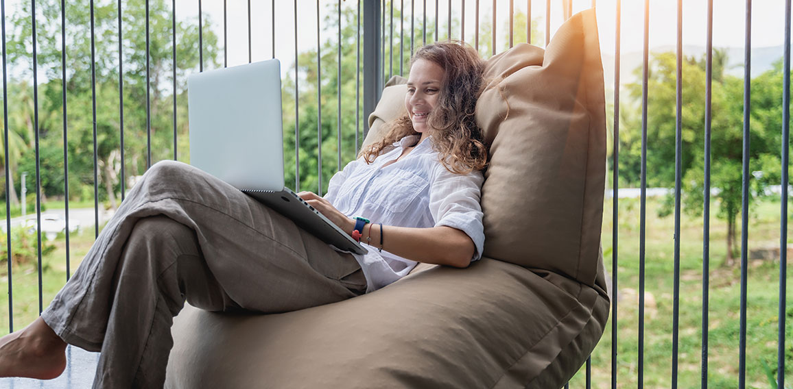 Happy beautiful young woman in a white shirt sits an  bean bag c