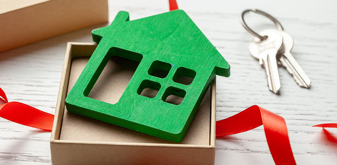 Gift box with red ribbon and house with keys. House as a gift