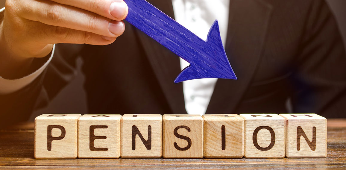 A man holds an arrow down over wooden blocks with the word Pension. Fall / reduction pension payments. Retirement. Financing retirees. Reduction of the pension fund. The low size of pensions.