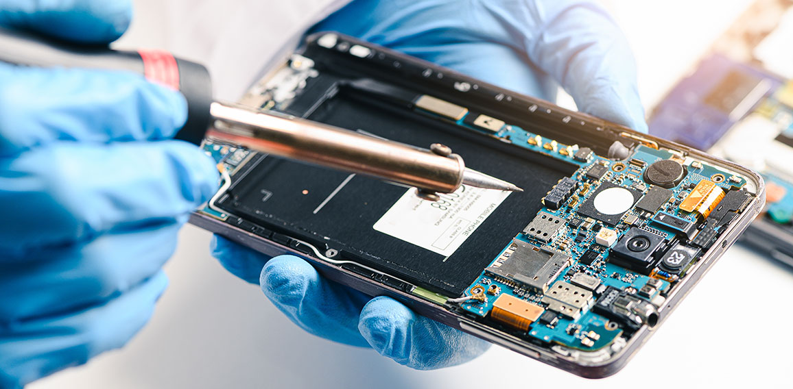 The technician repairing the smartphone's motherboard in the lab