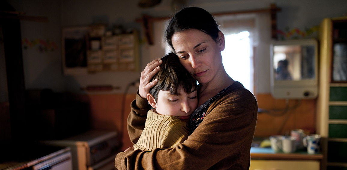 Portrait of sad poor mature mother hugging small daughter indoors at home, poverty concept.