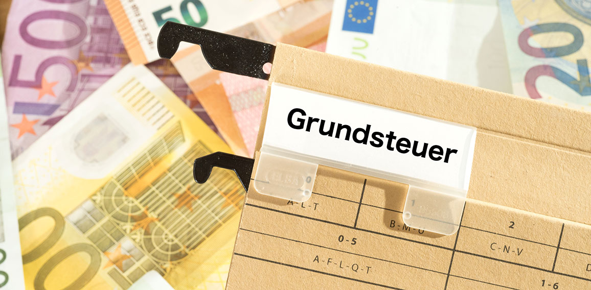 Euro Geldscheine und ein Ordner mit dem Aufdruck Grundsteuer