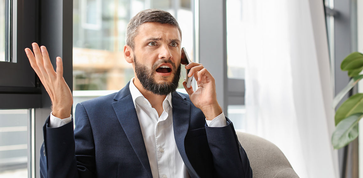 Emotional businessman talking on phone in office