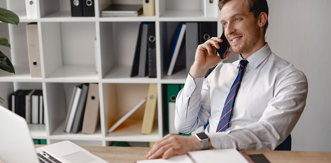 Relaxed man talking on the phone at work and smiling