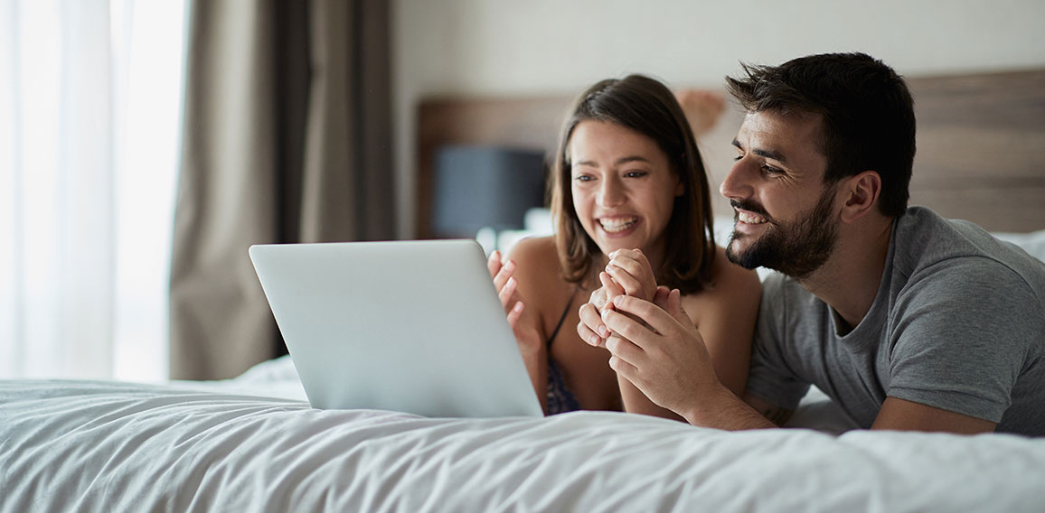 Man and woman at home surfing the net in bed