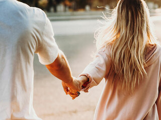 Crop couple holding hands on street