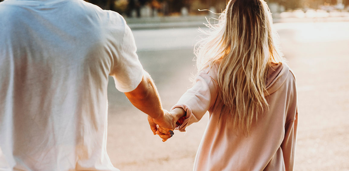 Crop couple holding hands on street