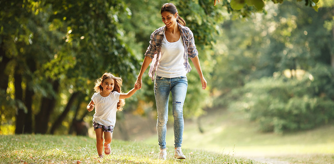 Mother and daughter playing and running around the park on beaut