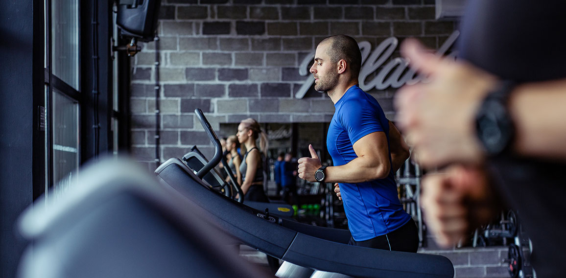 Young man in sportswear running on treadmill at gym.