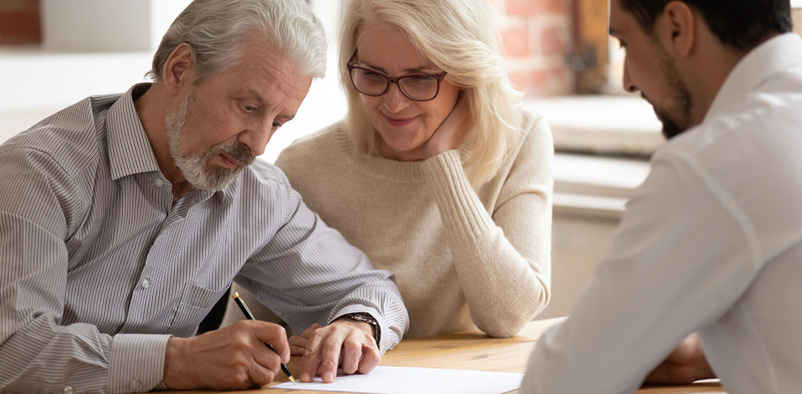 Happy mature couple close deal signing contract with realtor