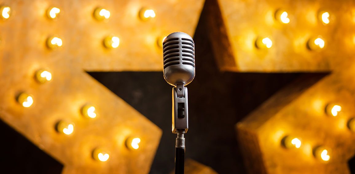 Microphone on theater or karaoke stage, golden luminous star on background