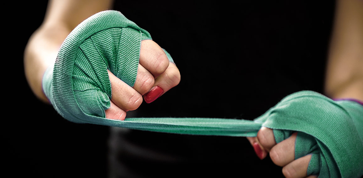 Woman is wrapping hands with pink boxing wraps