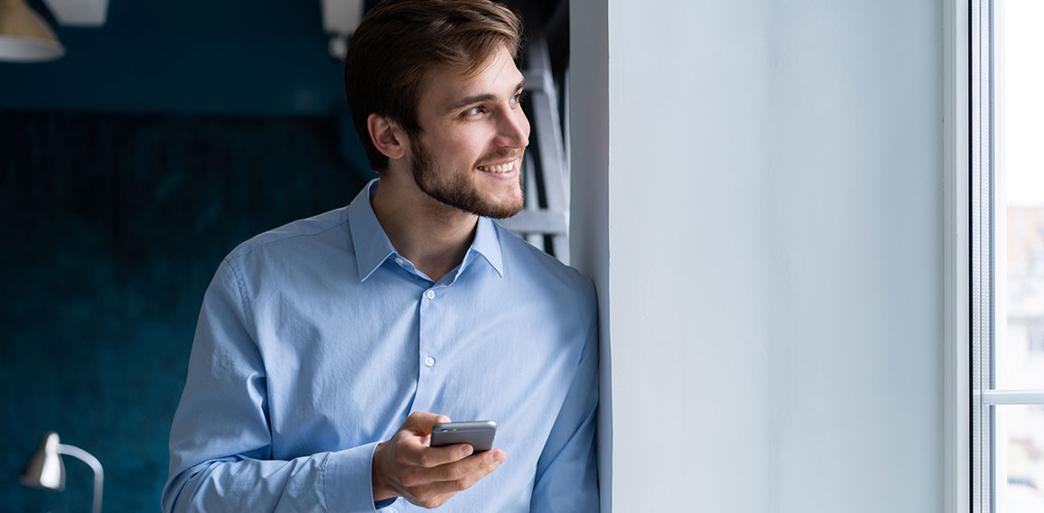 handsome young bearded business man in office using mobile phone indoors.