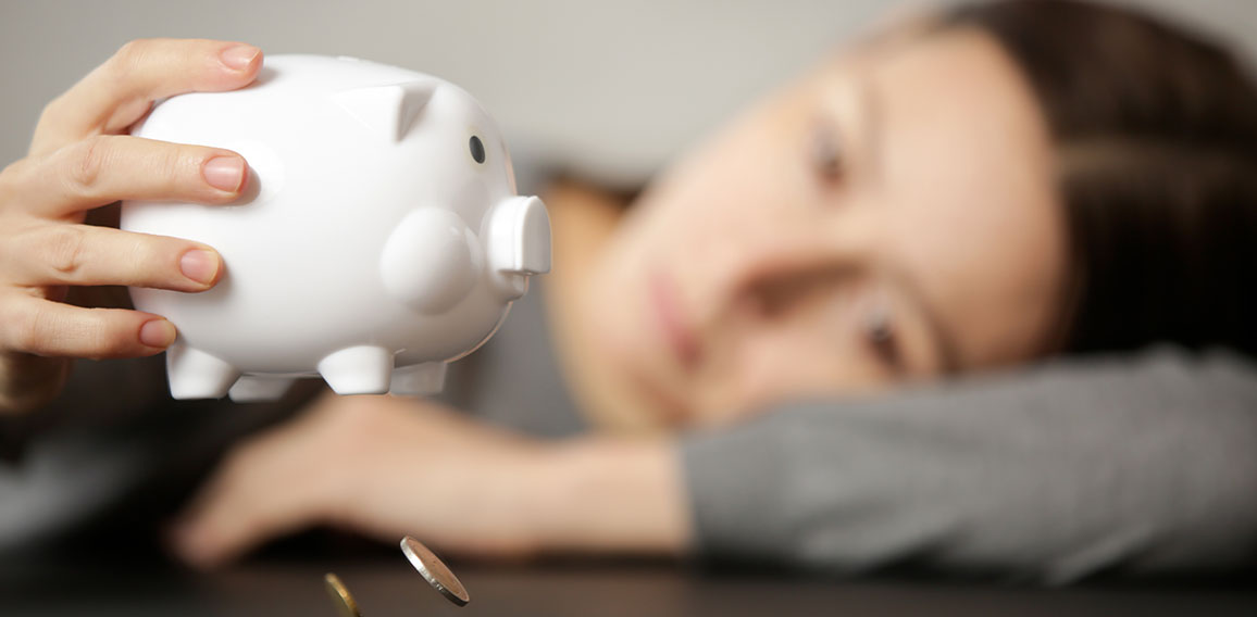 Unhappy woman shaking an empty piggy bank