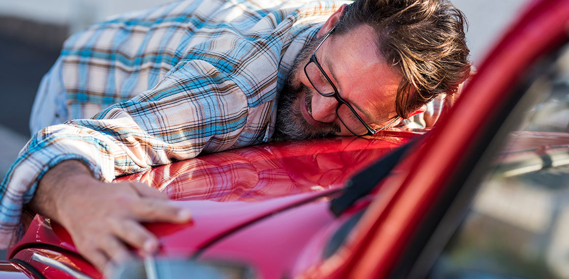 Handsome bearded man is hugging his new car and smiling - love f