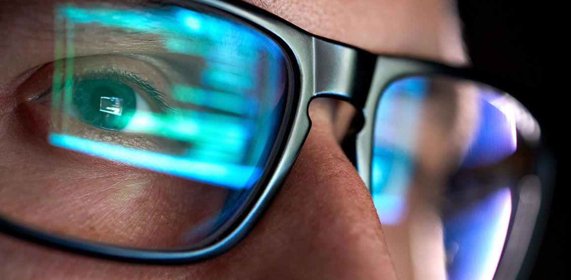 Developer coder looking on computer, programming code reflecting in glasses.