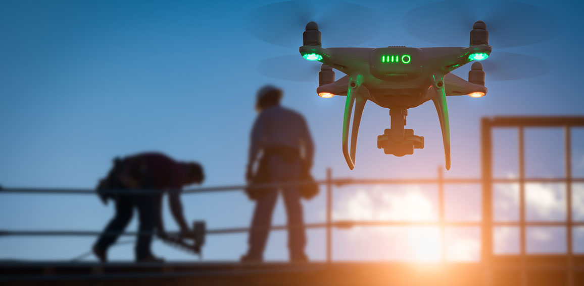 Silhouette of Unmanned Aircraft System Drone (UAV) Quadcopter Drone In The Air Over Building Under Construction.