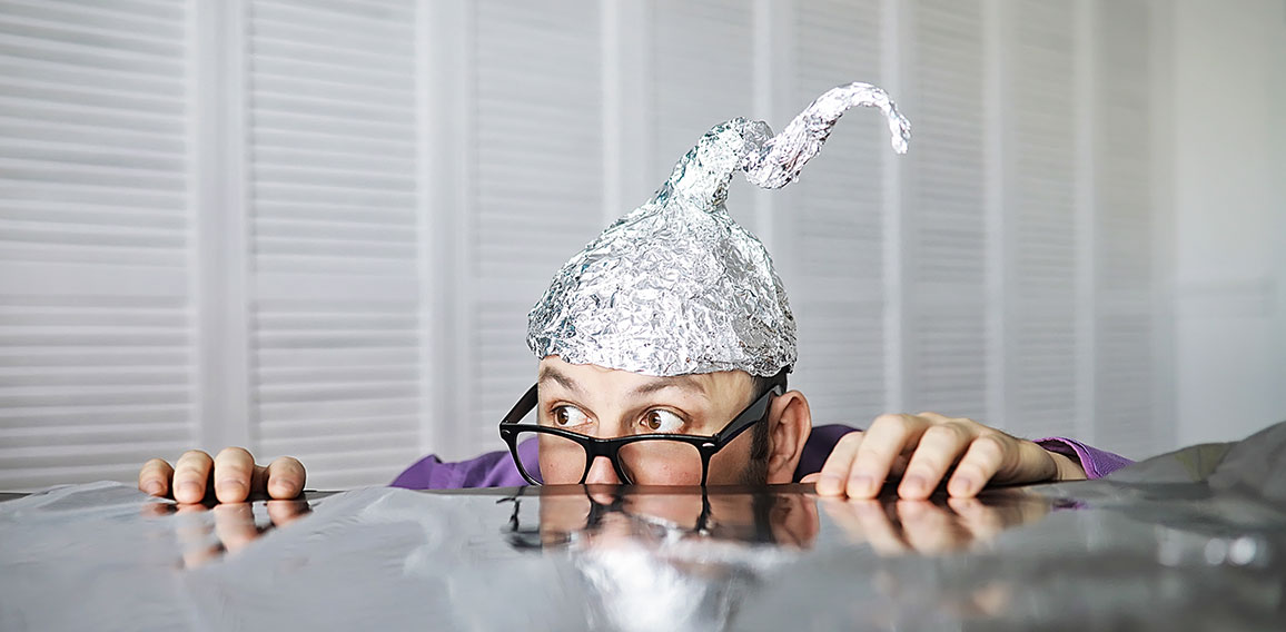 Bearded funny man in a cap of aluminum foil. Concept art phobias