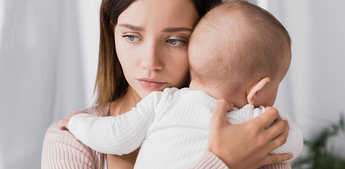 worried mother holding in arms baby boy and looking away