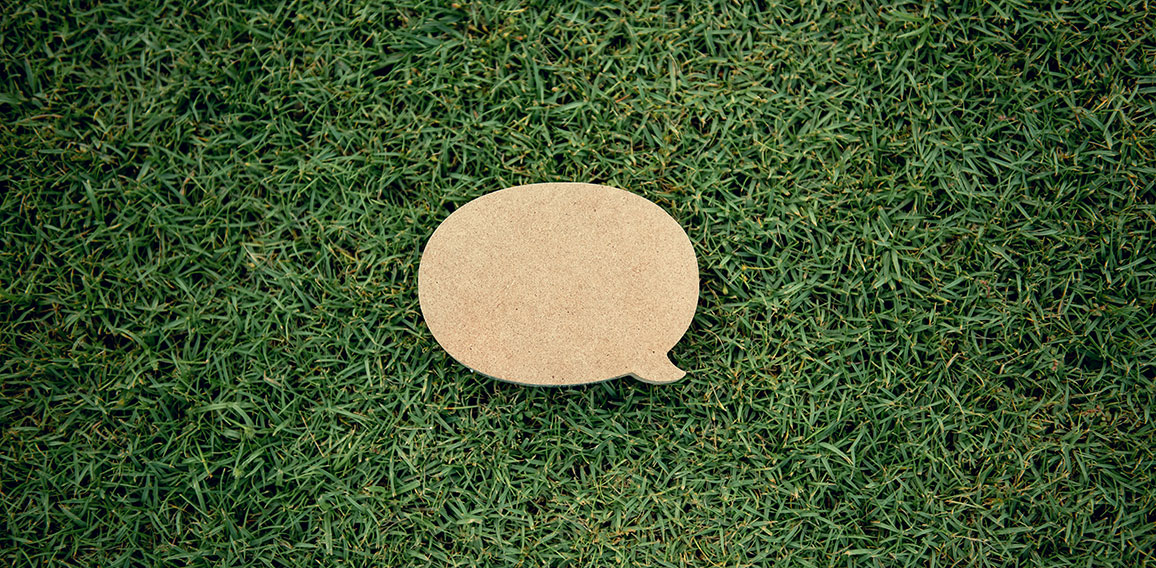 Blank yellow speech bubble pin on green grass background