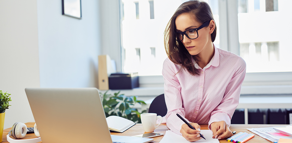 Busy oung woman working in office with documents and laptop