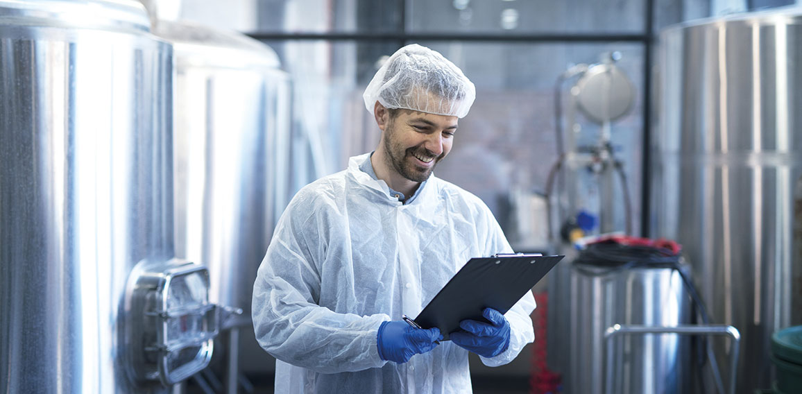 Industrial worker technologist in white suit with hairnet and pr