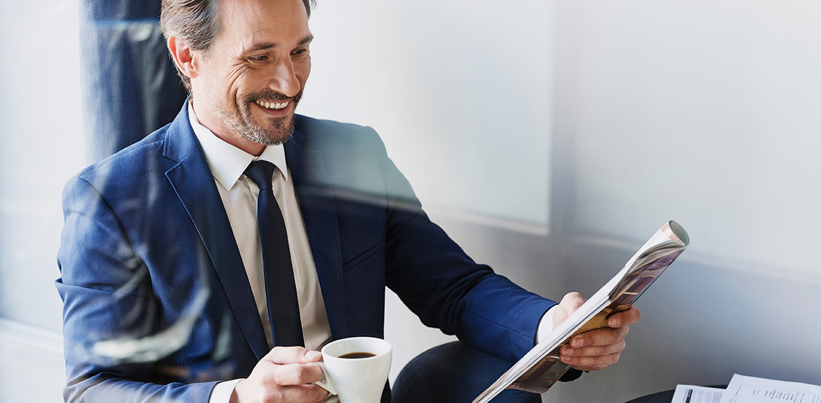 Cheerful businessman drinking coffee in cafe