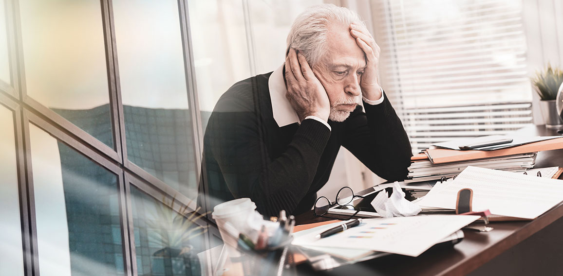 Overworked businessman sitting at a messy desk; multiple exposur