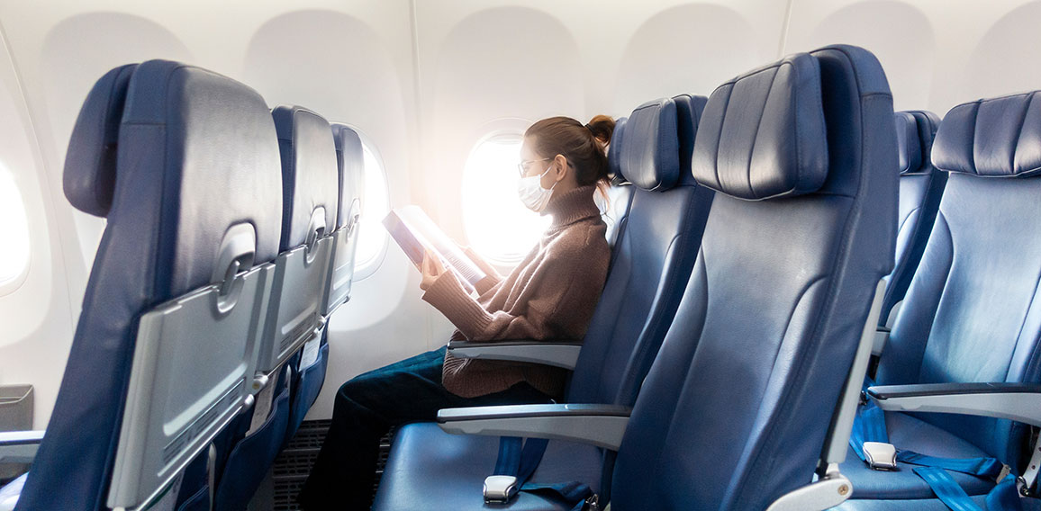 A young woman wearing face mask is traveling on airplane , New normal travel after covid-19 pandemic concept