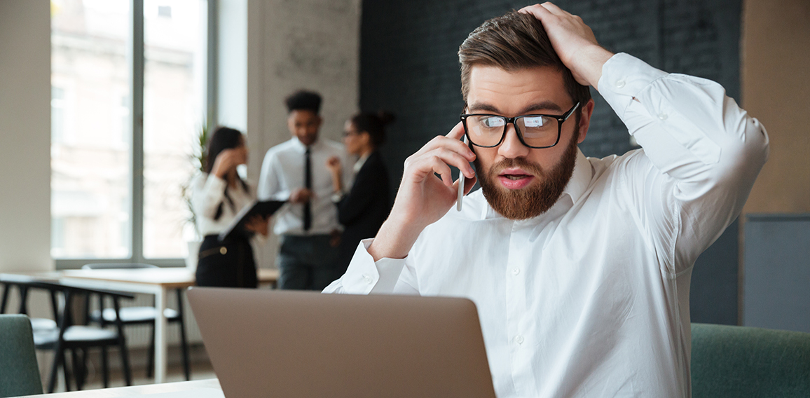 Shocked excited young caucasian businessman talking by mobile phone.