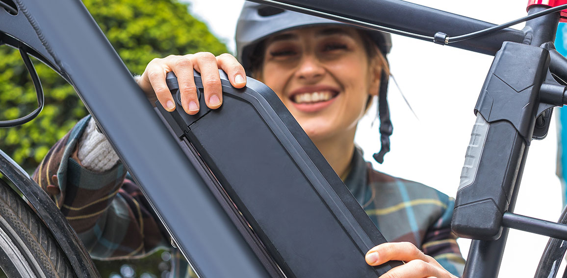 woman holding an electric bike battery mounted on frame