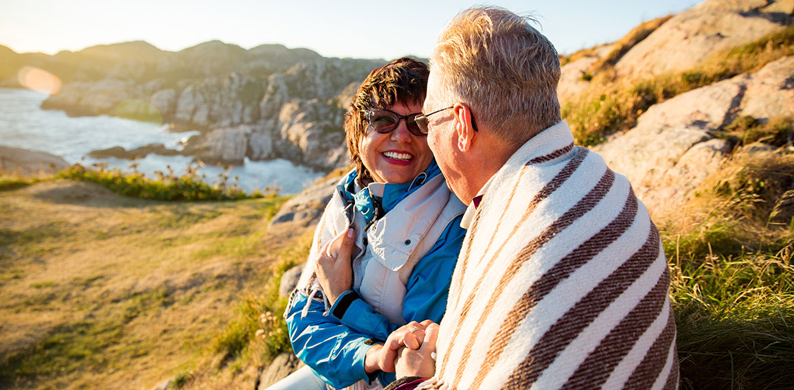 Loving mature couple hiking, sitting on windy top of rock, explo