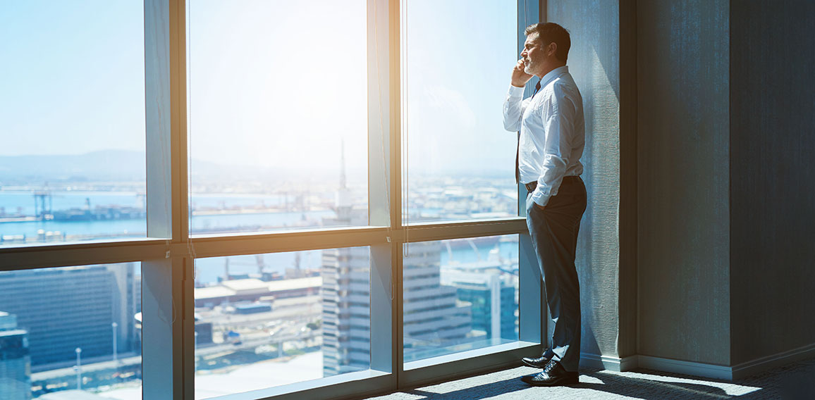 Mature business executive in top floor office space on phone