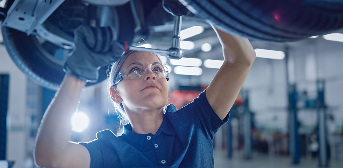 Portrait Shot of a Female Mechanic Working Under Vehicle in a Ca