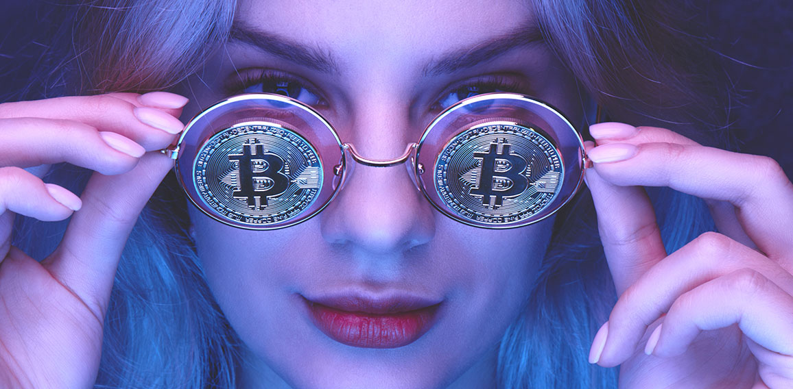 Portrait of a beautiful young blond woman with red lips in glasses with bitcoins close-up. Cryptocurrency concept. Creative neon lighting