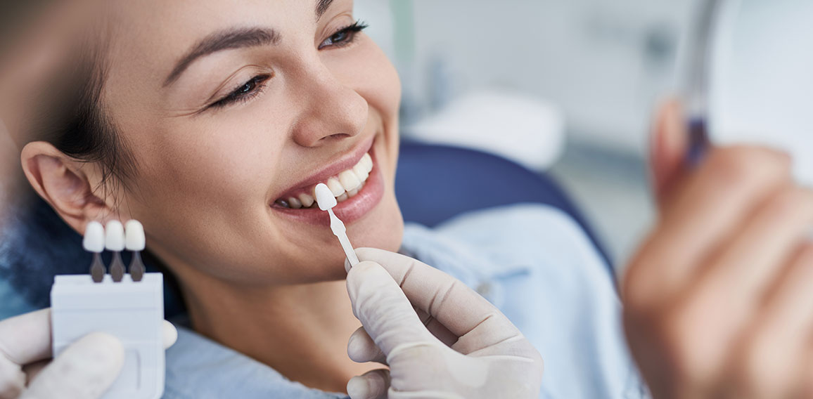 Male dentist choosing color for woman teeth