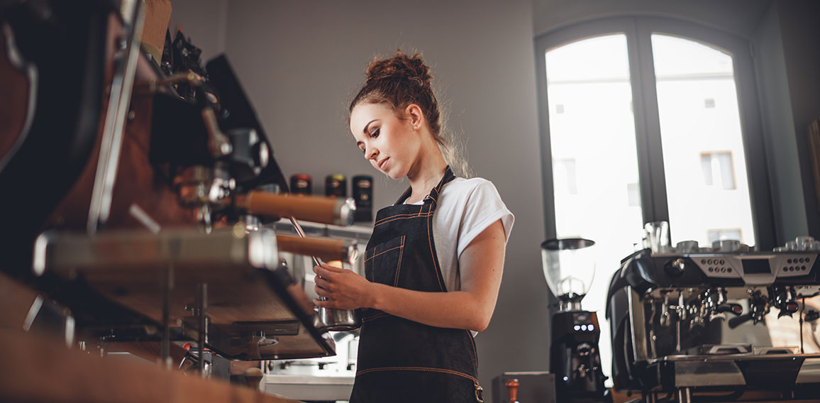 Portrait of professional barista woman in apron making coffee us