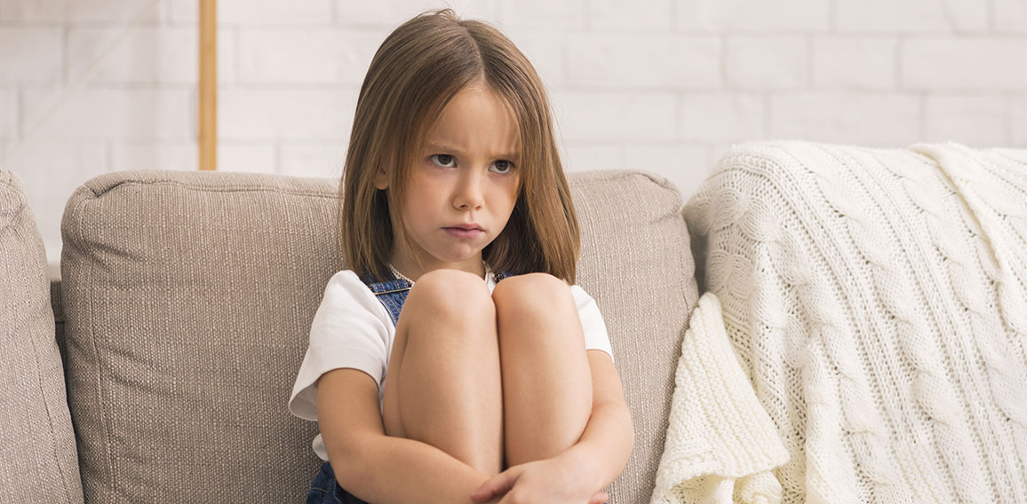 Concerned Little Girl Sitting Alone At Therapy Session With Children Psychologist