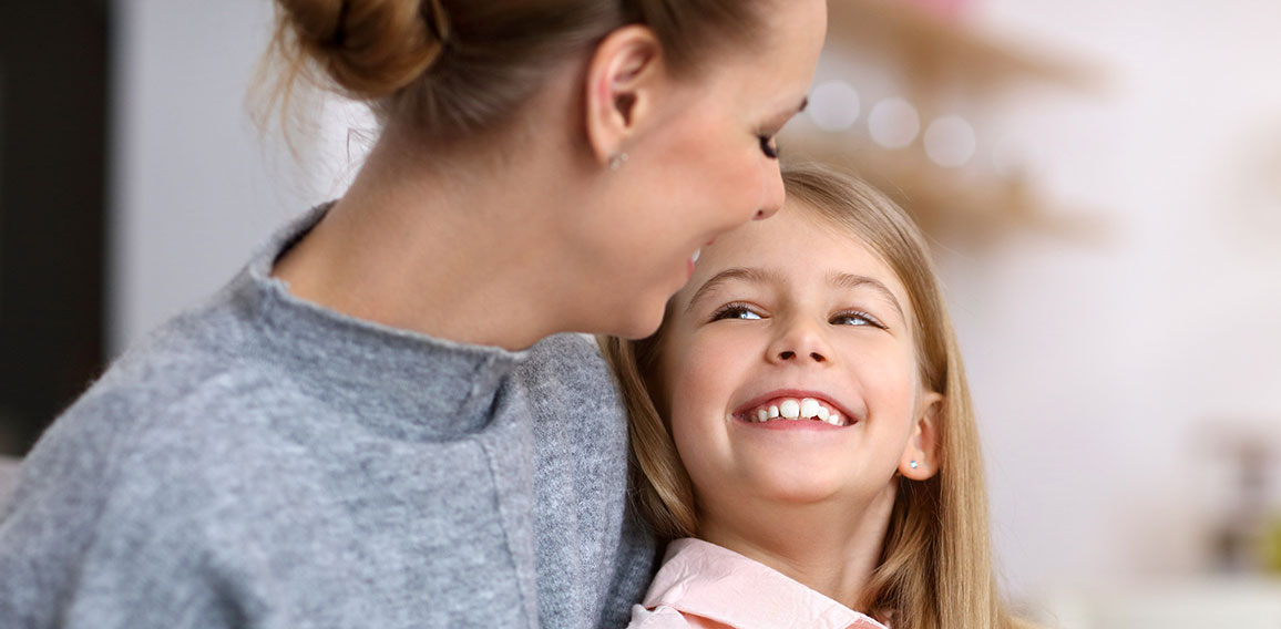 Young girl and her mother with piggybank sitting at table