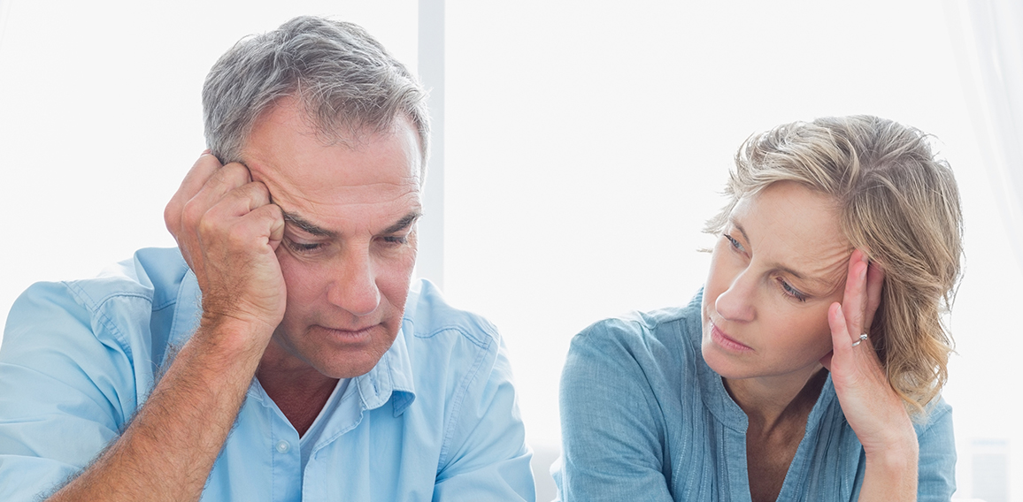 Worried couple using their laptop to pay their bills at home in the living room