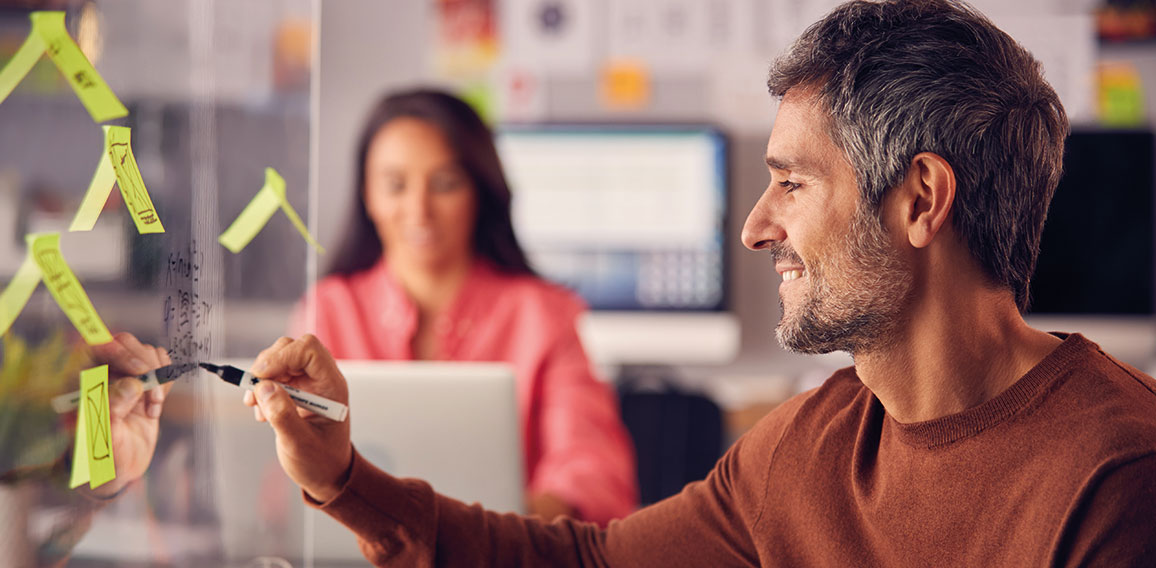 Brainstorming Creative Business Team Putting Ideas Onto Glass Screen In Office