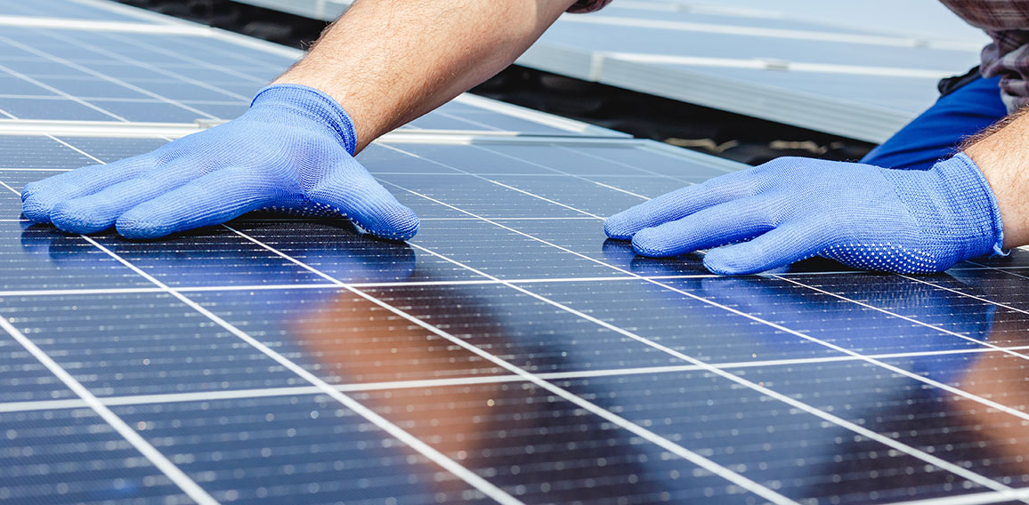 Male worker hands in glows on solar panel, technician installing solar panels on roof. Alternative energy sun energy power, ecological concept. Long web banner