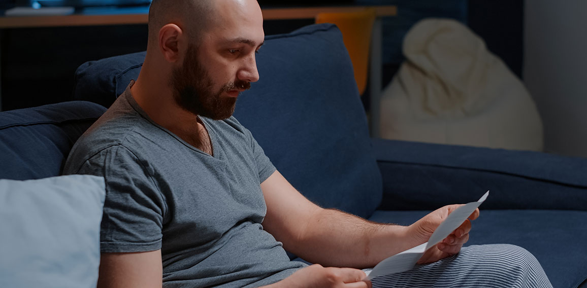 Angry stressed depressed man reading bad news in mail letter