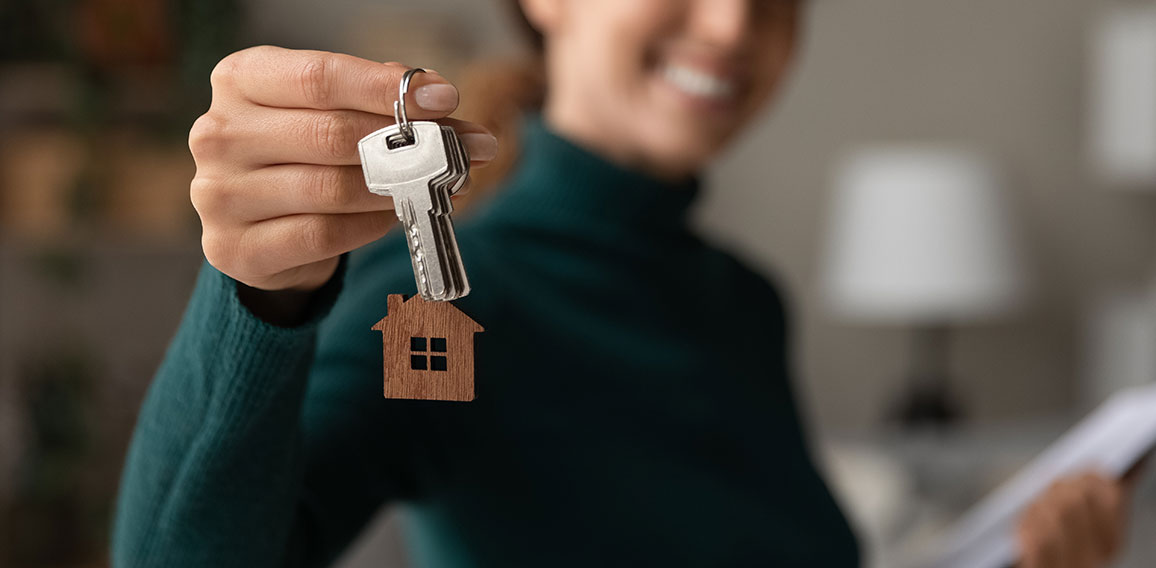 Close up focus on keys, smiling woman realtor selling apartment