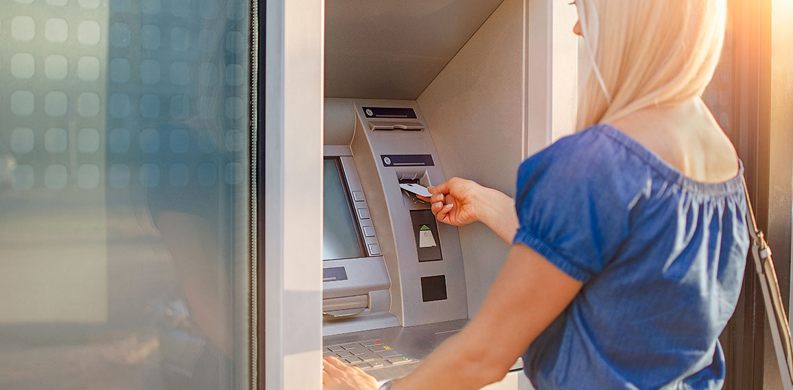 Young woman withdrawing money from credit card at ATM machine