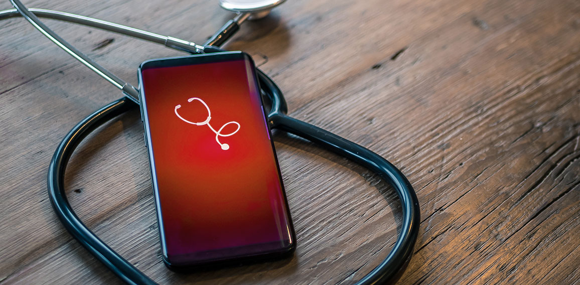 Mobile phone with healthcare app on wood table with stethoscope