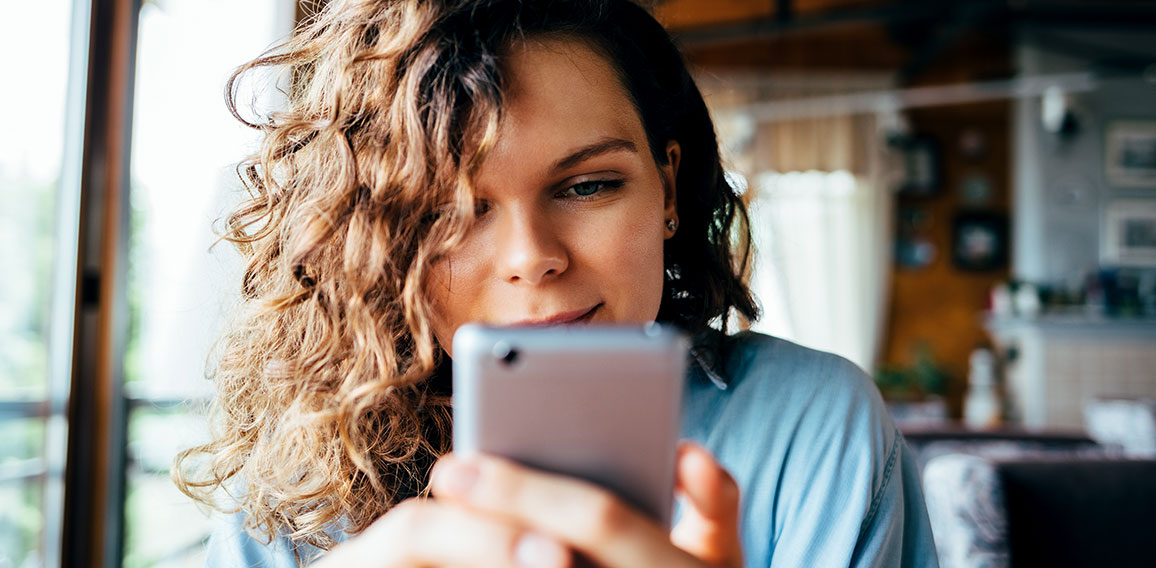 Close-up portrait of young woman texting on smart phone