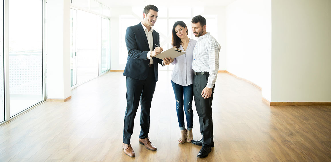 Realtor Explaining Agreement To Couple In New Apartment