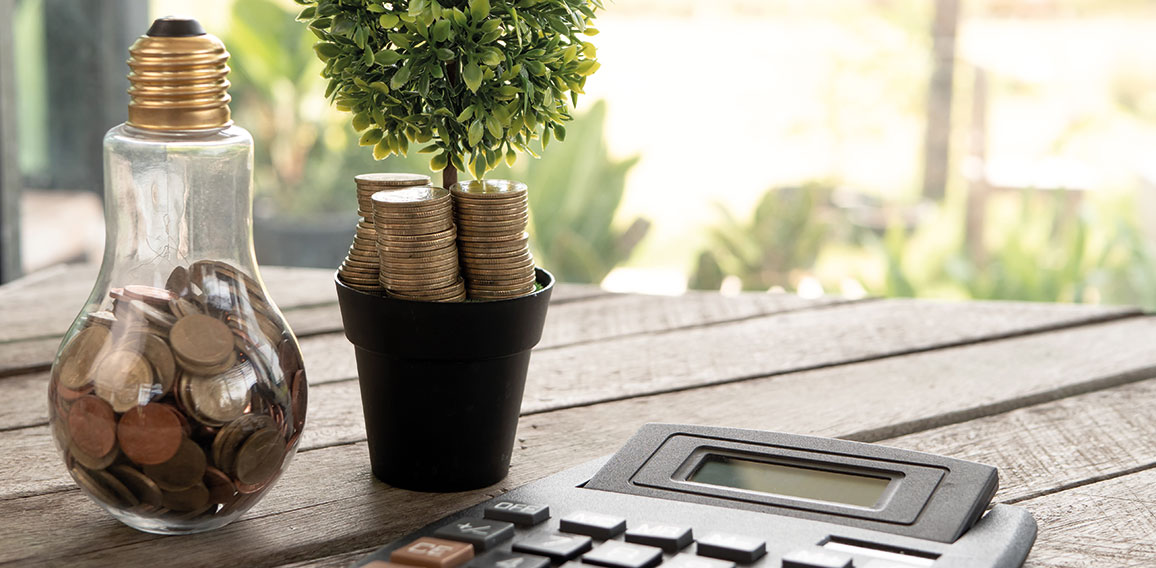 light bulb with coin and tree, calculator on wood table. Concept