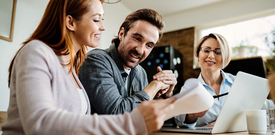 Bellow view of happy couple having a meeting with insurance agent.